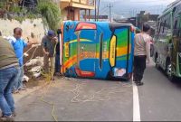Petugas kepolisian bersama warga saat mengevakuasi mikrobus yang terguling di Jalan Wonosobo-Dieng.