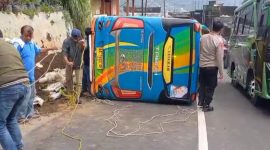 Petugas kepolisian bersama warga saat mengevakuasi mikrobus yang terguling di Jalan Wonosobo-Dieng.