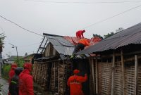 Petugas BPBD dan relawan bergotong royong memperbaiki rumah yang rusak di terjang angin puting beliung.