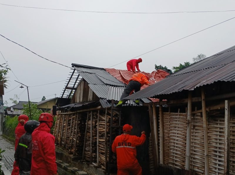 Petugas BPBD dan relawan bergotong royong memperbaiki rumah yang rusak di terjang angin puting beliung.