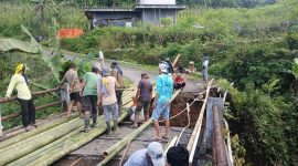 Warga bergotong royong membangun jembatan darurat dari bambu agar pejalan kaki dan roda dua tetap bisa lewat.