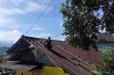 Warga melakukan perbaikan atap yang rusak terkena angin kencang.