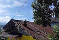 Warga melakukan perbaikan atap yang rusak terkena angin kencang.
