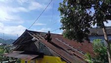Warga melakukan perbaikan atap yang rusak terkena angin kencang.